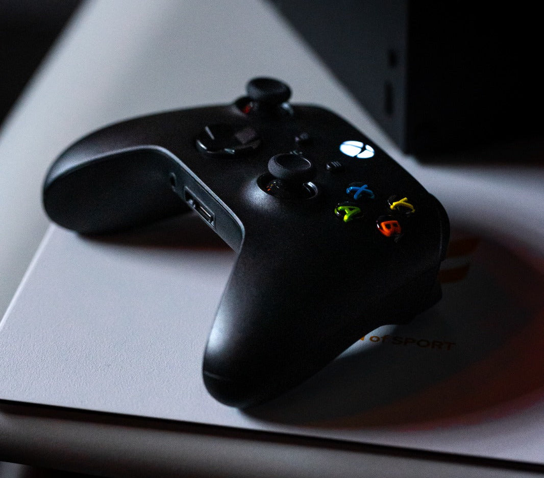 Black gaming controller on a white surface with a blurred background